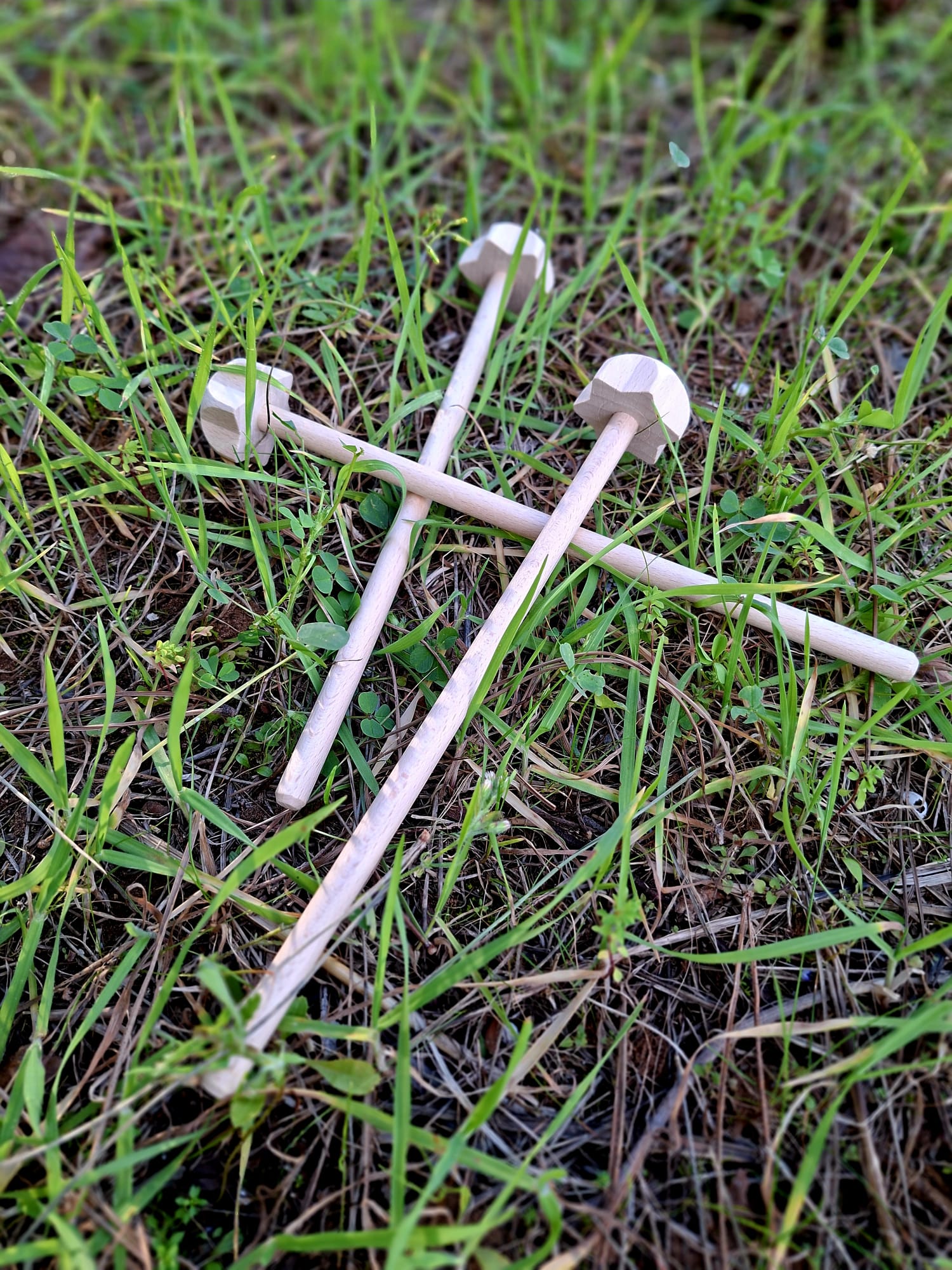 Espumador artesanal de madera para preparar cacao ceremonial, colocado sobre hierba natural.