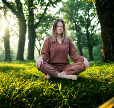 Mujer meditando en la naturaleza con cacao ceremonial, sentada sobre césped y conectando con la calma a través de la respiración consciente.